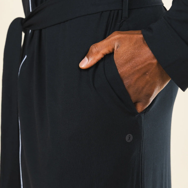 Hand slipped into the front pocket of a black robe, belt hanging loose