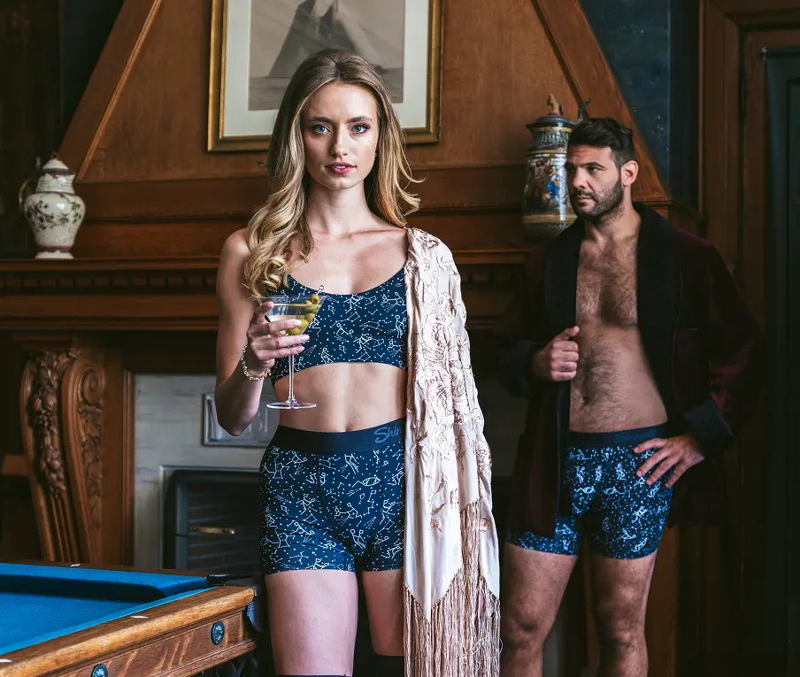A couple in matching navy print underwear in a wood-panelled games room